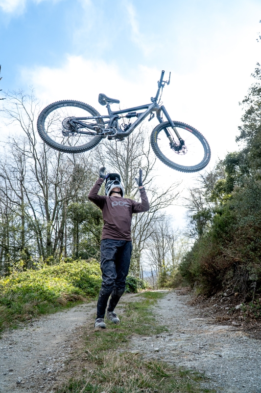 Mountainbiker hebt sein Bike am Trail hoch